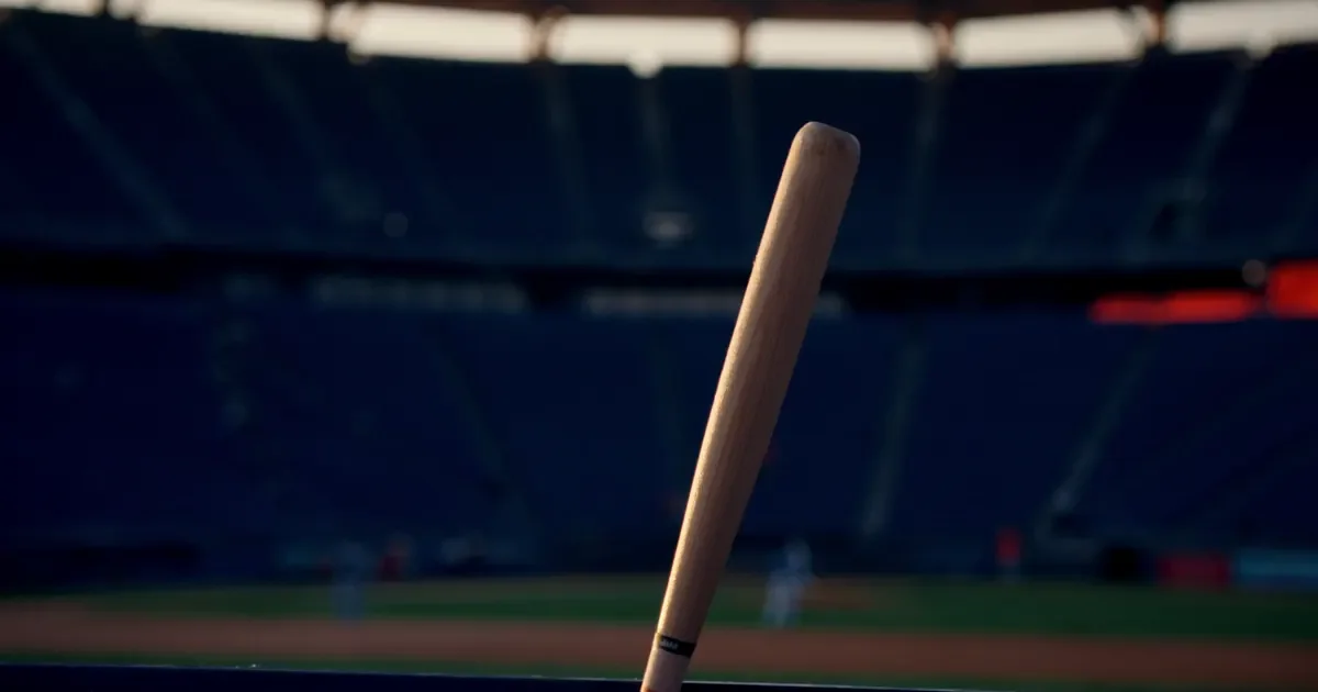 A wooden baseball bat leaning in front of empty stadium seats