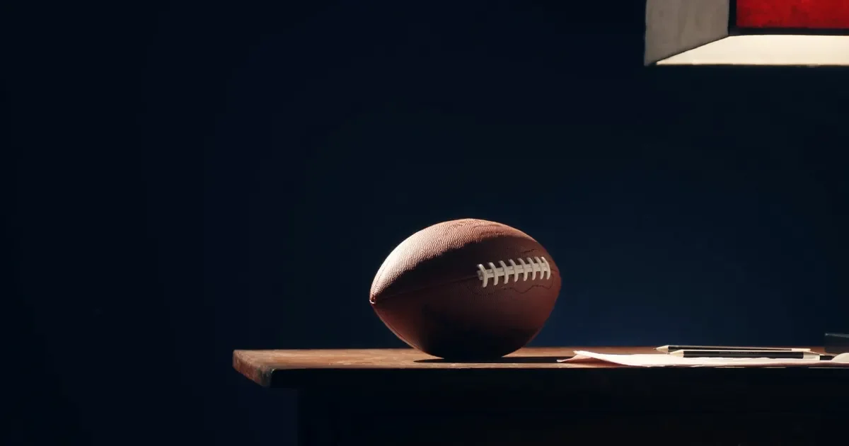 An American football on a wooden table in a dark room