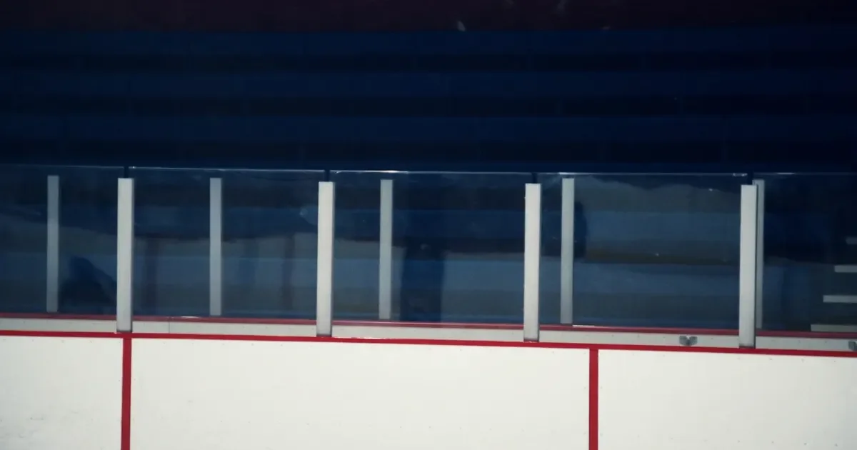 An empty hockey penalty box behind glass, white ice in the foreground